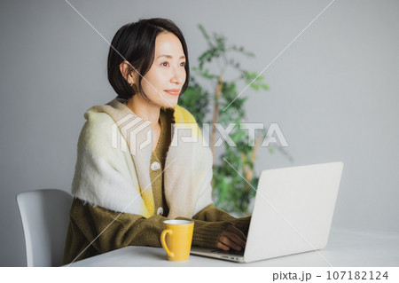 コーヒーを飲みながらパソコンを見る女性 107182124
