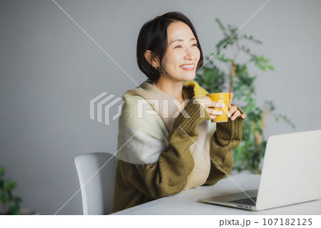 コーヒーを飲みながらパソコンを見る女性 107182125