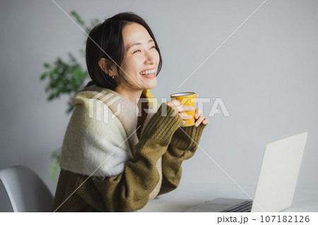コーヒーを飲みながらパソコンを見る女性 107182126