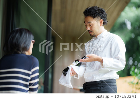 ワインの説明をするオーナーシェフ 107183241
