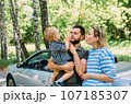 Mom, dad and little son in a convertible car. Summer family road trip to nature 107185307