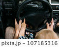 Dad shows his little son how to drive car while sitting behind wheel 107185316