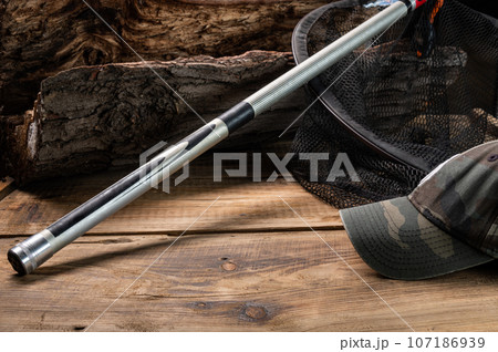 Butt of a fishing rod on a wooden stump. Camouflage fisherman's cap. Fishing screensaver. 107186939