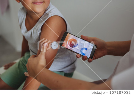 Boy with diabetes checking blood glucose level at home using continuous glucose monitor. 107187053
