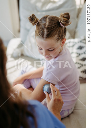 Nurse applying a continuous glucose monitor sensor to the arm of a diabetic girl. 107187120