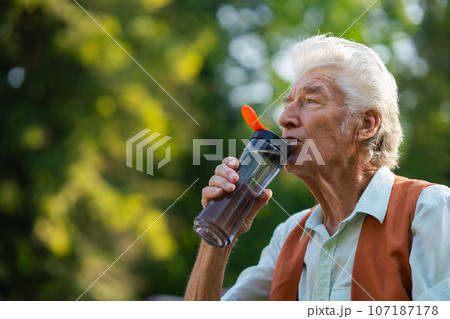 Senior man drinking water outdoor to better manage his diabetes. 107187178