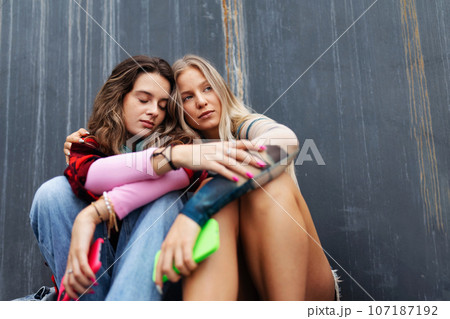 Gen Z friends sitting together outdoors in the city, comforting each other. Gen Z friends sitting together outdoors in the city, comforting each other. 107187192