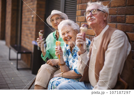 Portrait of three senior friends in the city, eating ice cream on a hot summer day. 107187297