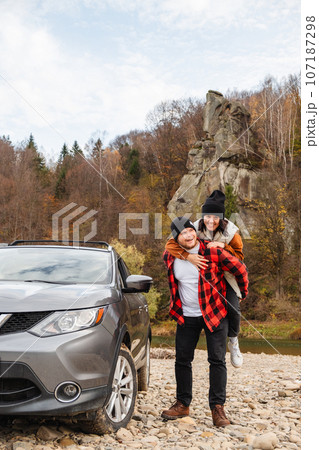 happy couple piggyback car at rocky mountain beach 107187298