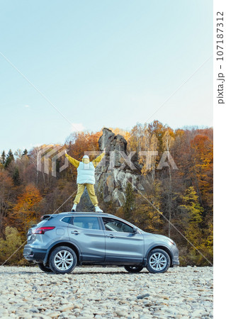 happy woman at car roof enjoying the view of autumn river in carpathian mountains 107187312