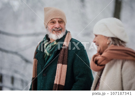 Close-up of elegant senior man walking with his wife in the snowy park. Close-up of elegant senior man walking with his wife in the snowy park. 107187341