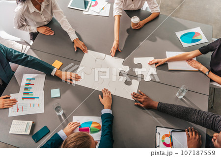 Businessmen working together to build a puzzle as teamwork, partnership and integration concept 107187559