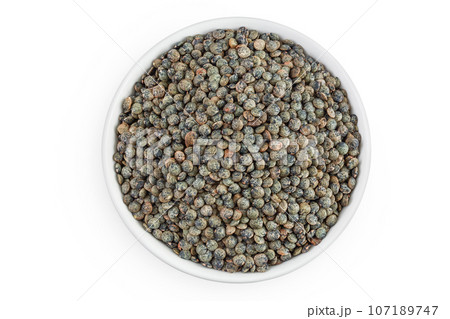 raw french green lentils in ceramic bowl isolated on white background. Top view. Flat lay raw french green lentils in ceramic bowl isolated on white background. Top view. Flat lay 107189747