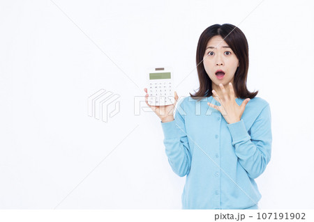白い背景の前で電卓を持ちびっくりしている30代の女性 107191902