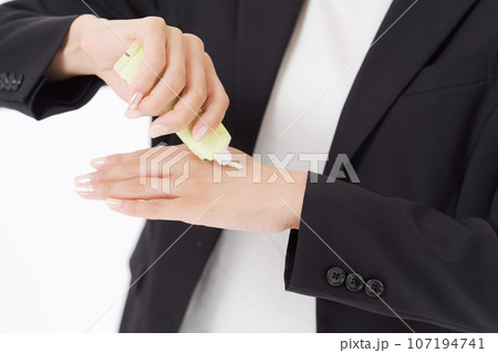 ハンドクリームを塗るビジネスウーマンの手元 107194741