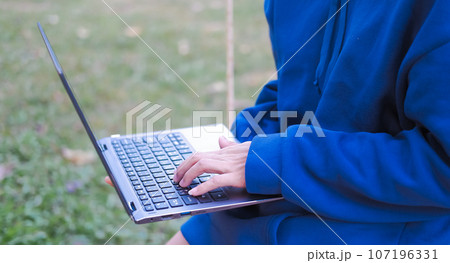 Woman relaxing with laptop in garden Suitable for making infographics. 107196331
