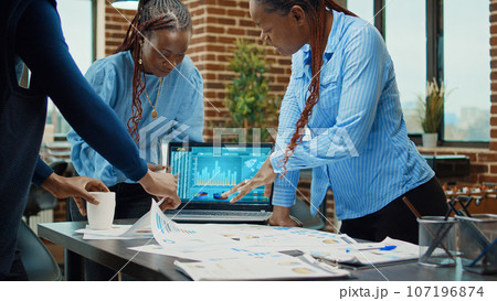 Workers discussing about annual reports, analyzing executive statistics with laptop and files. Business partners meeting in boardroom to create professional project for development. 107196874
