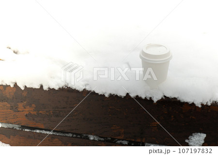 Hot warming drink in Eco paper cup. Mock up Cardboard coffee or tea Cup in the snow in winter day. Copy space zero waste recycle cup white snow-covered field 107197832
