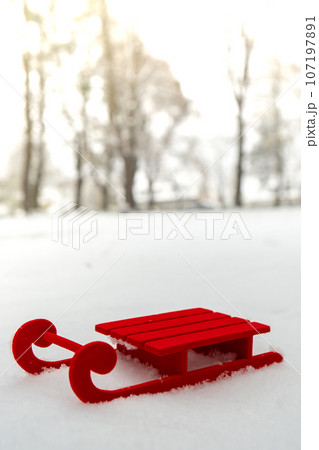 Small Red sled on snow background in beautiful winter day. Copy space for text. Mock up for product greeting card or wallpaper. Christmas 107197891