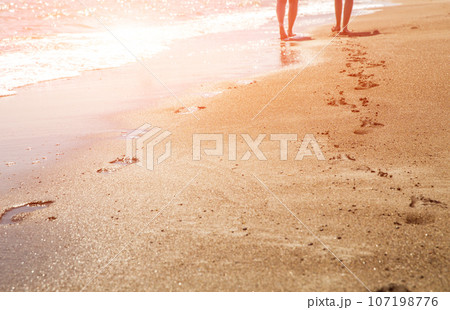 Beach, wave and women footprints at sunset time with sun flare Beach, wave and women footprints at sunset time with sun flare 107198776