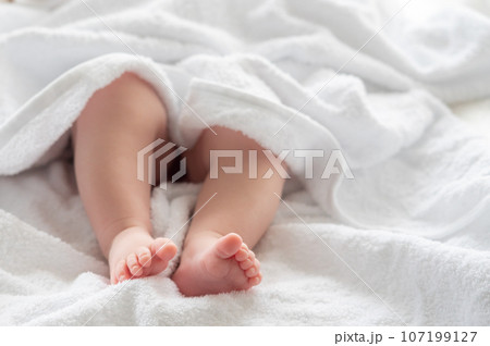 Baby's legs wrapped in a white towel's embrace. Concept of nurturing moments after bath 107199127