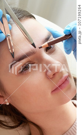 Cosmetologist measures the proportions of the eyebrows with the ruler. 107199264