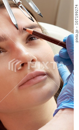 Cosmetologist measures the proportions of the eyebrows with the ruler. 107199274