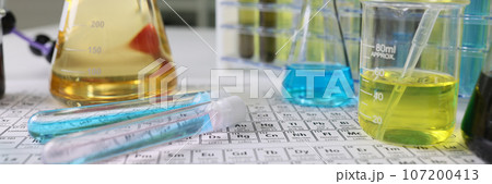 Research laboratory glassware with reagents on periodic table of chemical elements. 107200413