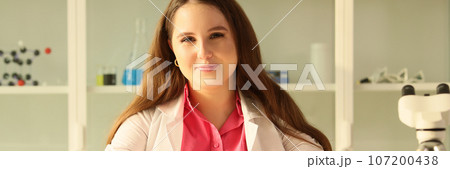Young female scientist in research laboratory smiling and looking at camera. 107200438