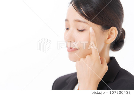 目元を指差すスーツ女性の写真 107200452