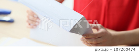 Close-up of office manager holding stack of blank paper while sitting at desk. 107200474