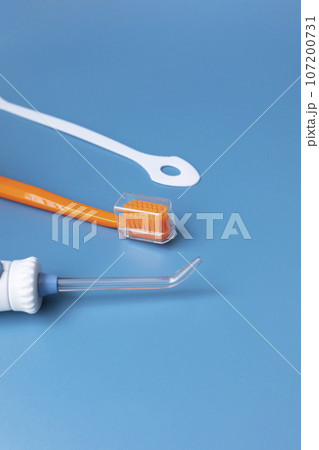Dental Cleaning Set, Oral Hygiene. Toothbrush, Oral Irrigator, Floss, Tongue Scraper On Blue Background. Flat Lay Of Dental Care Tools, Tooth Hygienic Equipment. Vertical Plane. Copy Space For Text. Dental Cleaning Set, Oral Hygiene. Toothbrush, Oral Irrigator, Floss, Tongue Scraper On Blue Background. Flat Lay Of Dental Care Tools, Tooth Hygienic Equipment. Vertical Plane. Copy Space For Text. 107200731