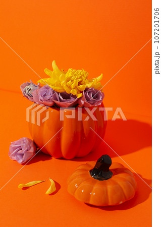Pumpkin vase with flowers on orange background Pumpkin vase with flowers on orange background 107201706