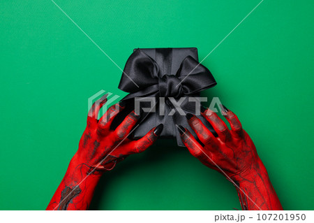 Spooky, red monster hands hold a gift 107201950
