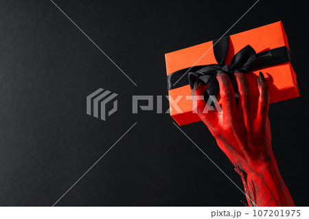 Spooky, red monster hands hold a gift Spooky, red monster hands hold a gift 107201975