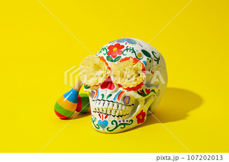 Mexican skull, flowers and maracas on yellow background 107202013