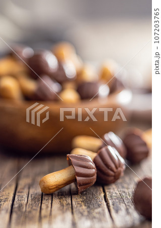 Candy in the shape of a mushroom. Chocolate mushrooms on wooden table. 107203765