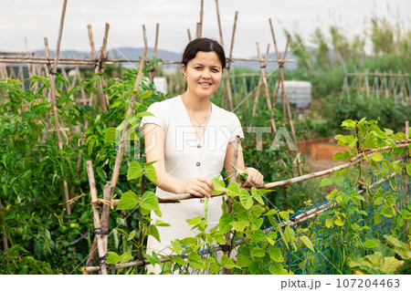 Female farmer enjoying while working in vegetable garden. 107204463