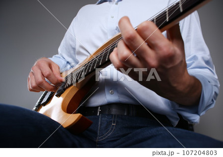 Male arms playing classic shape electric guitar 107204803