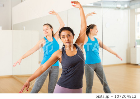 Hispanic woman practicing ballet dance moves in choreographic studio 107204812
