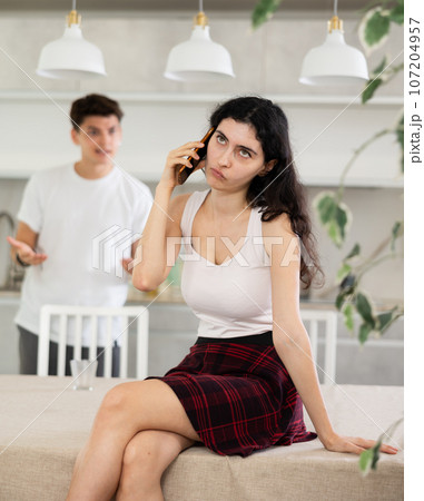Young guy quarrels with young woman talking on phone Young guy quarrels with young woman talking on phone 107204957
