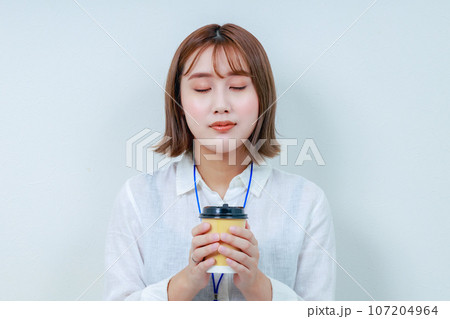 温かい飲み物を両手で持ってホッとする女性 温かい飲み物を両手で持ってホッとする女性 107204964