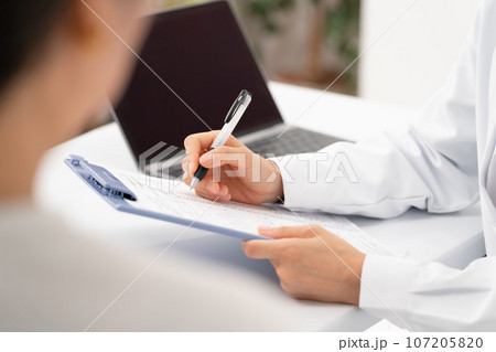 対面で問診する医者と患者　手元 107205820