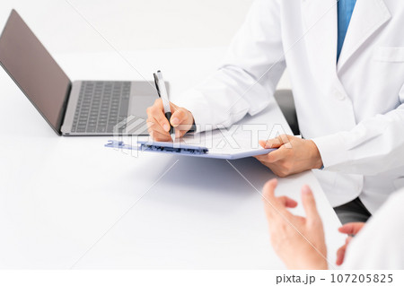 対面で問診する医者と患者　手元 107205825