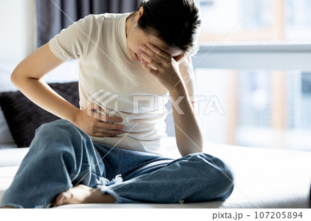 Asian young woman touch abdomen pain,sit in her bed,premenstrual syndrome,teen girl having period cramps,abdominal pain during menstrual period,Menstruation,Dysmenorrhea,Gynecology,Health care concept Asian young woman touch abdomen pain,sit in her bed,premenstrual syndrome,teen girl having period cramps,abdominal pain during menstrual period,Menstruation,Dysmenorrhea,Gynecology,Health care concept 107205894