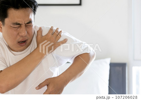 Stressed asian middle aged man suffering from shoulder pain,shoulder dislocation,aching numbness and weakness,tired male patient with Dislocated shoulder joint,discomfort caused by illness or injury 107206028