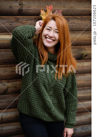 Laughing red-haired middle-aged woman with a maple leaf Laughing red-haired middle-aged woman with a maple leaf 107206625