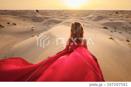 Woman in sands dunes of desert at sunset 107207581