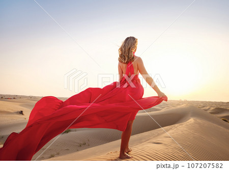 Woman in sands dunes of desert at sunset 107207582