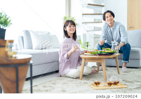 リビングでランチをする若いカップル リビングでランチをする若いカップル 107209024